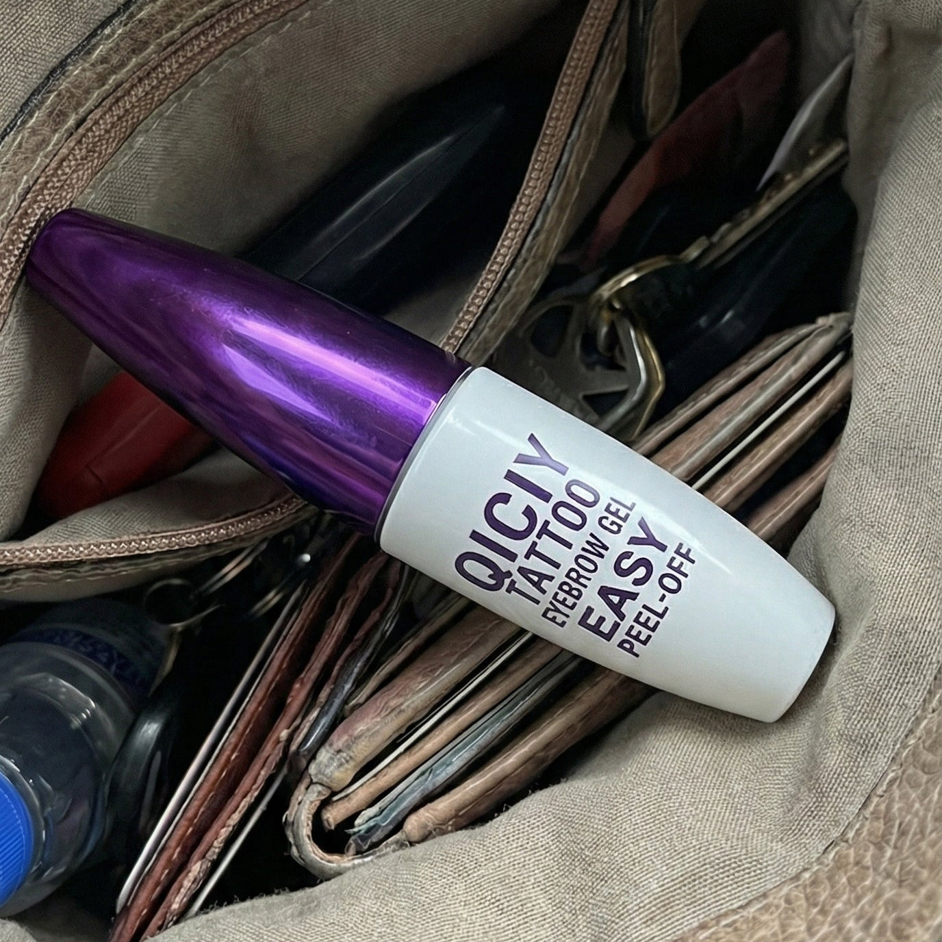 Purple and white bottle of Olay Total Effects 8-in-1 Serum in a brown leather bag.